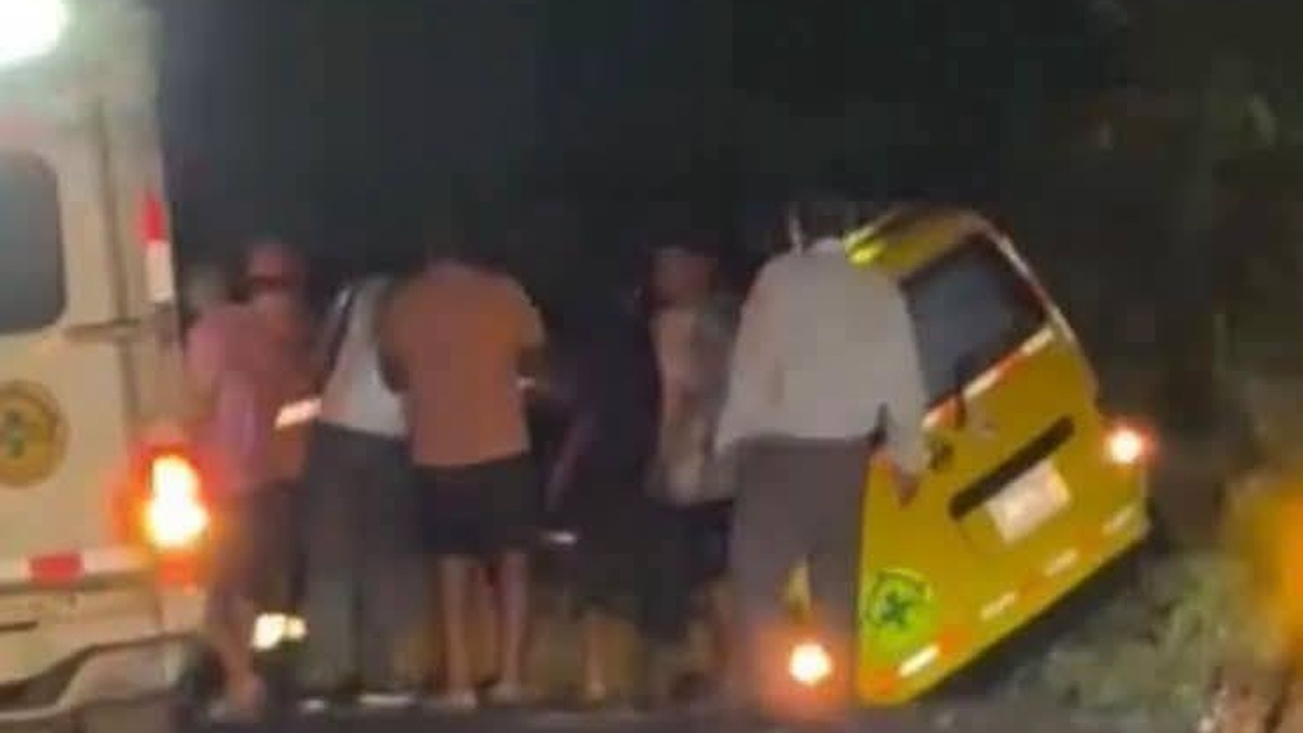 Ambulancia amarilla de Comandos de Salvamento volcada de lado junto a la calle, de noche