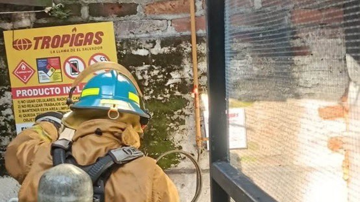 Bombero con equipo de respiración revisa la zona de cilindros de gas junto a un rótulo de Tropigas
