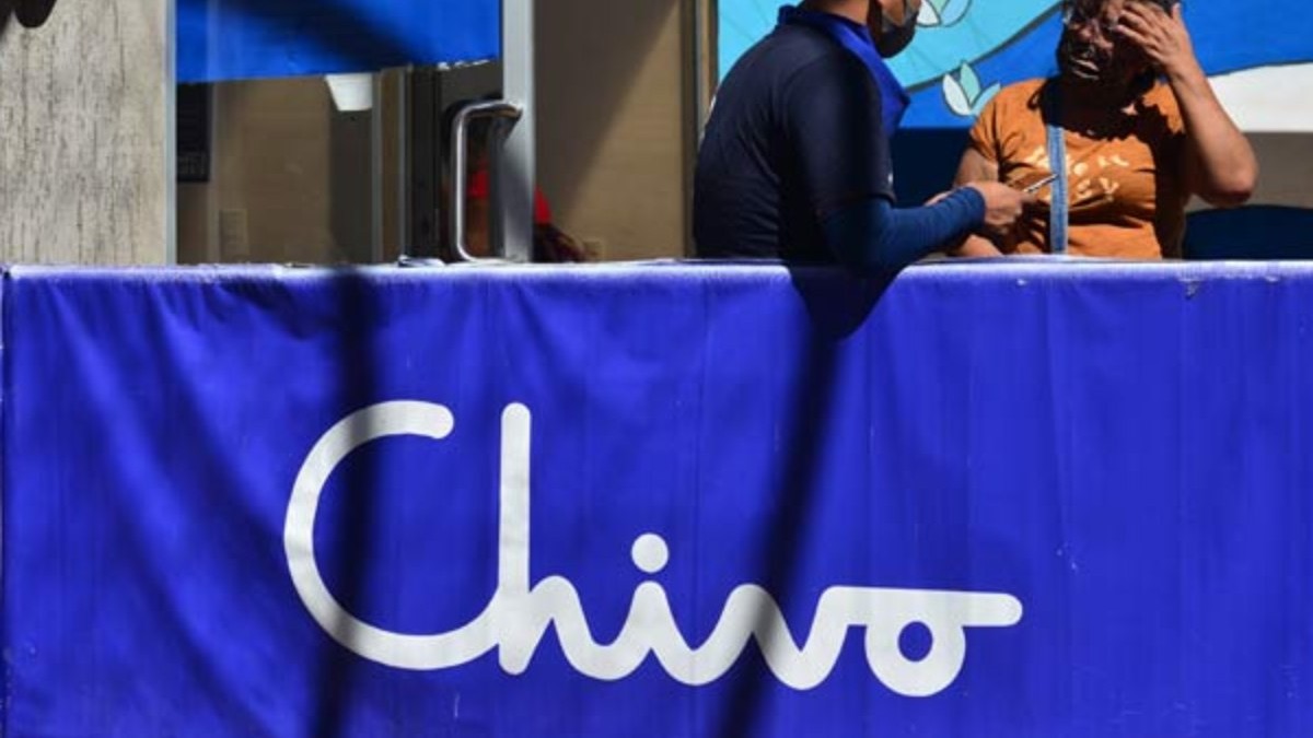 Una mujer con la mano en la cabeza frente a un empleado en un punto de atención de Chivo