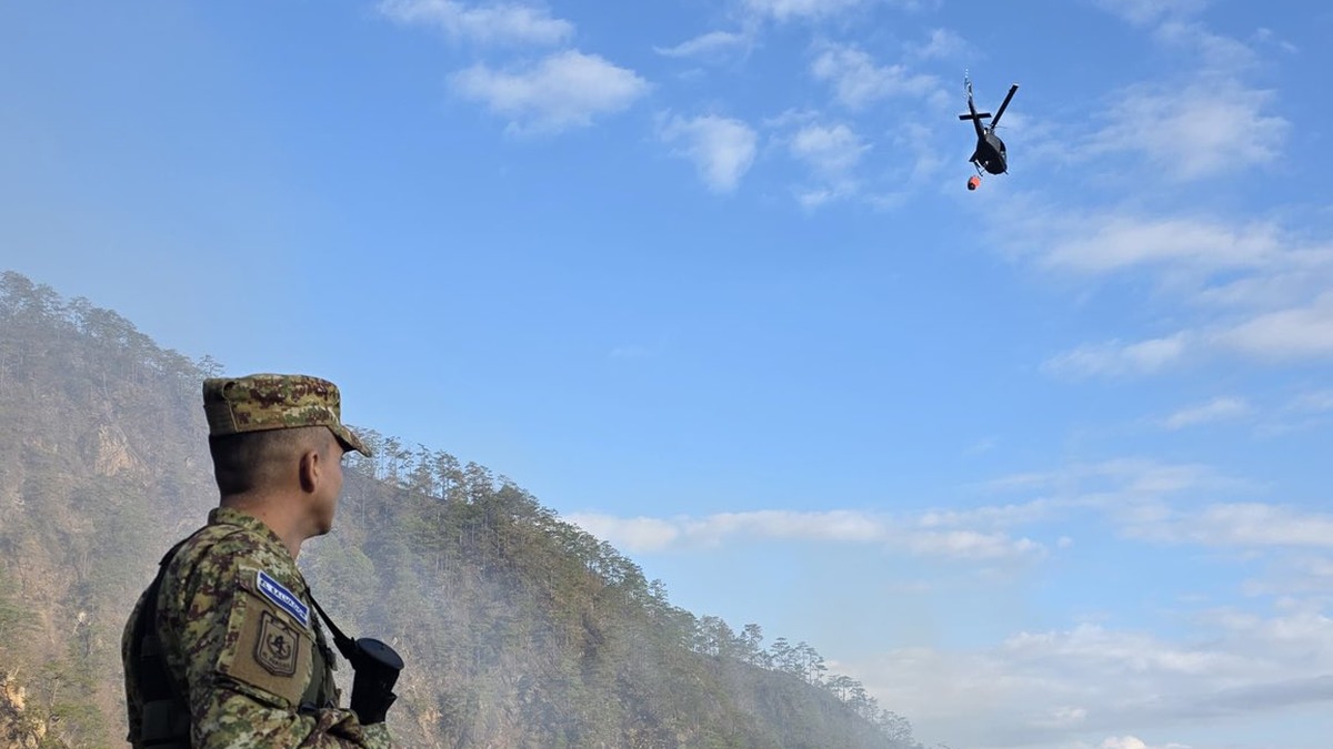 Soldado de la Fuerza Armada de El Salvador observa un helicóptero de la Fuerza Aérea (foto de archivo)