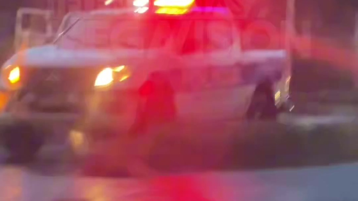 Patrulla de la PNC bajo la lluvia frente al desvío de Atecozol, en la carretera a Sonsonate, tras el choque de una moto con un pick-up