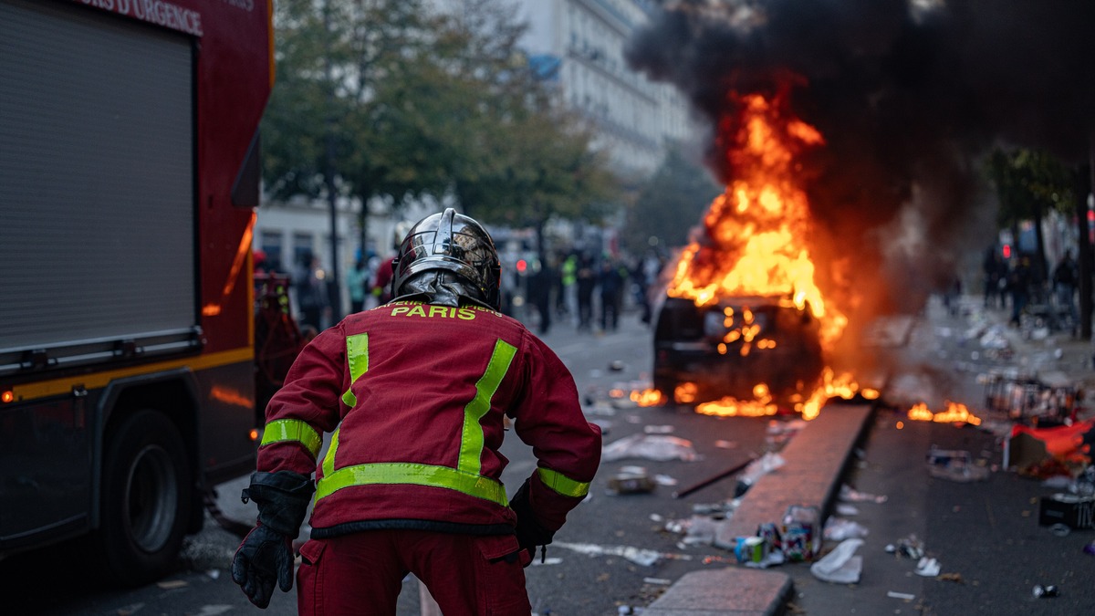 Un bombero de París se acerca a un carro en llamas durante los disturbios del 17 de octubre de 2026