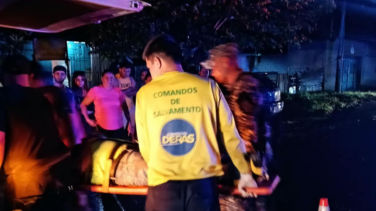 Socorristas de Comandos de Salvamento suben a un herido en camilla a una ambulancia, de noche, en Sonzacate