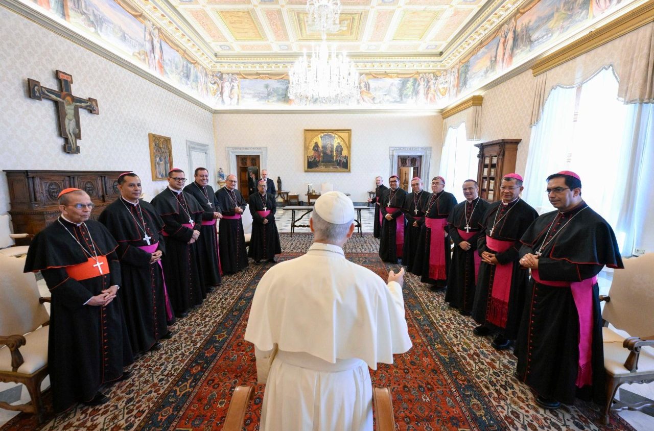 El papa León XIV, de espaldas, saluda a los obispos salvadoreños de pie en semicírculo