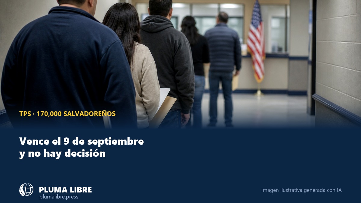 Un grupo de personas de espaldas, con carpetas en la mano, hace fila en el pasillo de una oficina federal de inmigracion de Estados Unidos, con una bandera estadounidense al fondo
